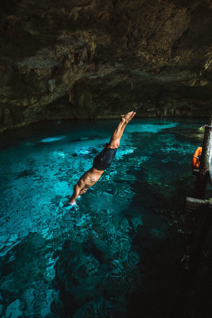 a man diving into a cenote in tulum
